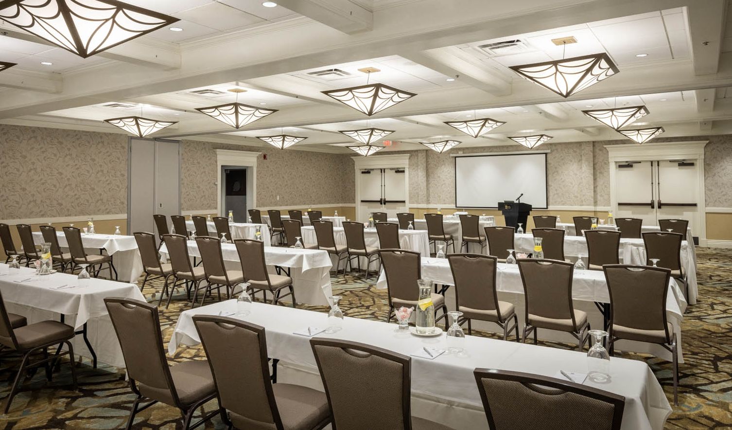 A function/conference room with rows of tables and a speaker's podium set up in the front of the room