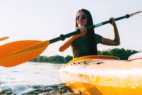 Woman in foreground paddling orange kayak, man in background also paddling a similar kayak